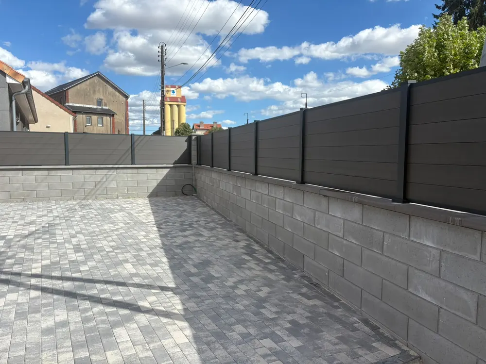 Cour pavée bordée d'une clôture à lames anthracite
