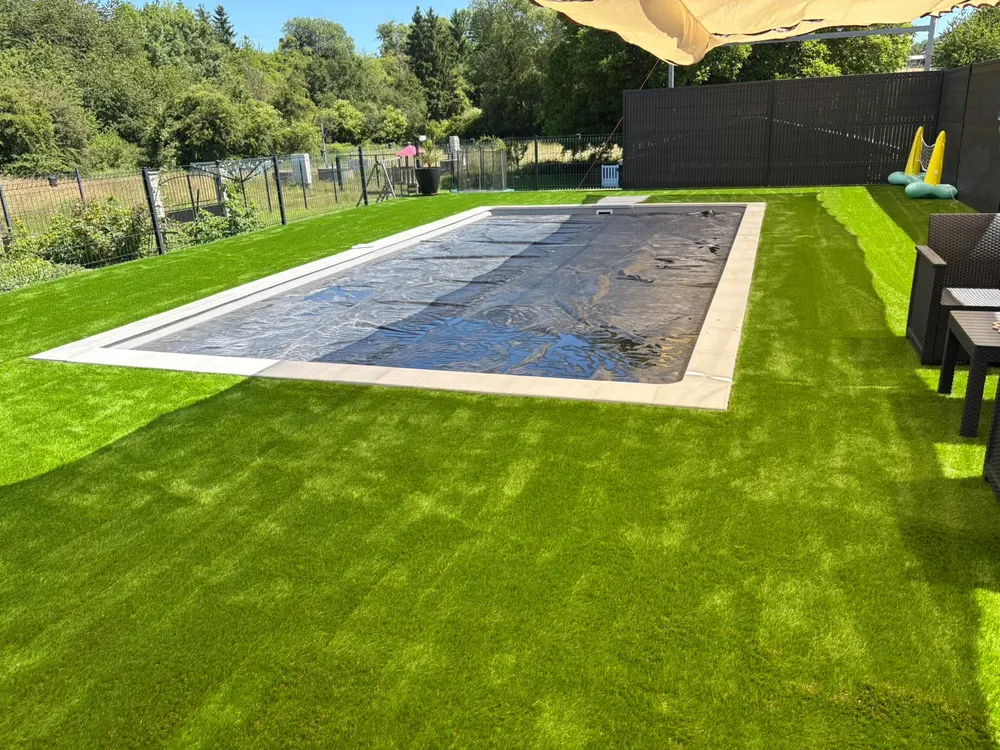 Gazon et aménagement paysager autour d'une piscine couverte