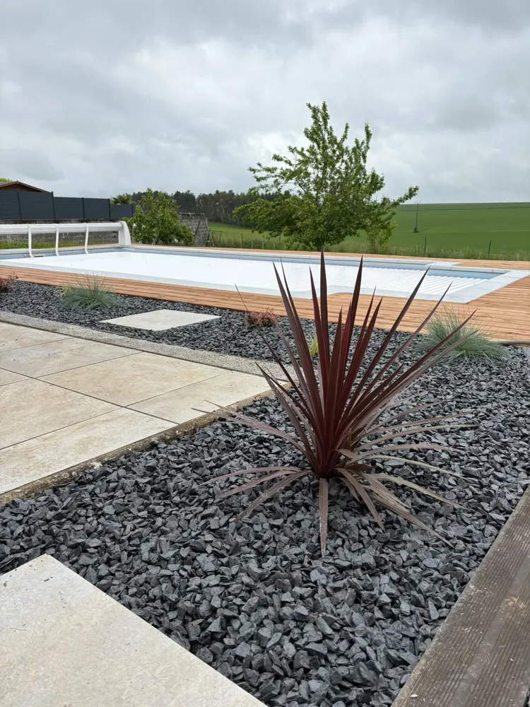 Massif minéral planté à côté d'une terrasse bois et d'une piscine