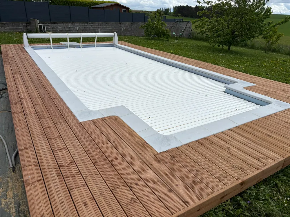 Terrasse bois réalisée autour d'une piscine à volet roulant